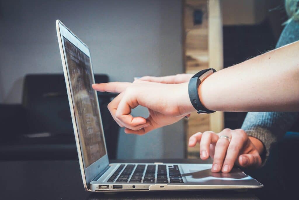 A person points at the screen of a laptop.